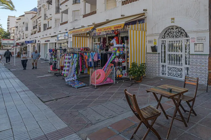 A pedestrian street with colorful shop displays and outdoor café seating.