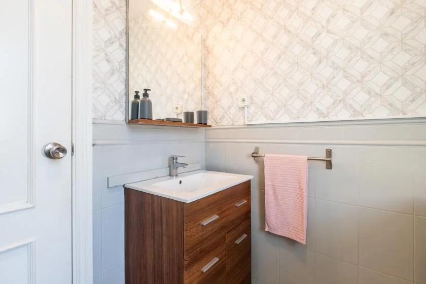 A bathroom vanity with a sink and a pink towel hanging on the wall.