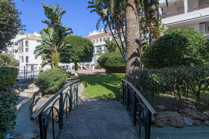 A landscaped courtyard with a stone path, greenery, and surrounding white buildings.