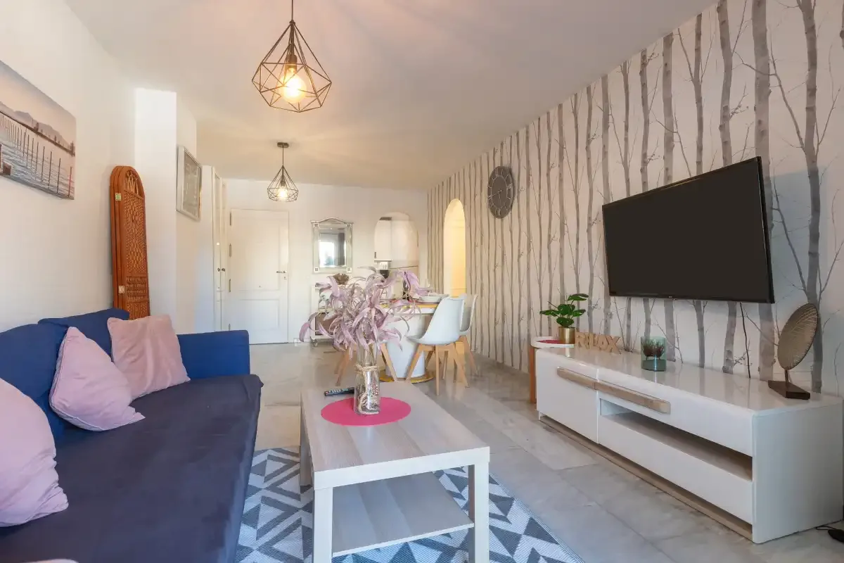 A living room with a sofa, coffee table, and wall-mounted television.