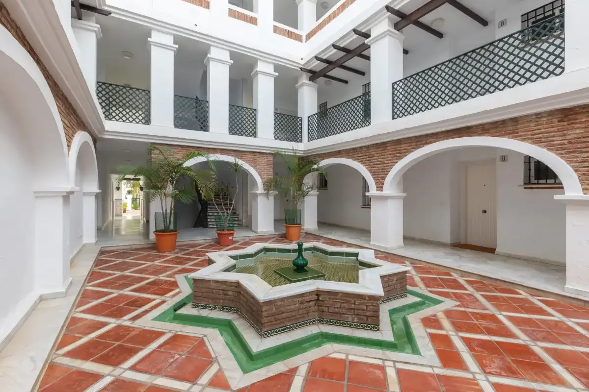 An indoor courtyard with arched walkways, balconies, and a central fountain.