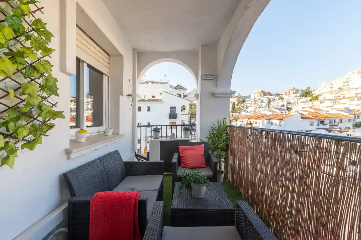 A covered balcony seating area overlooks a hillside neighborhood.