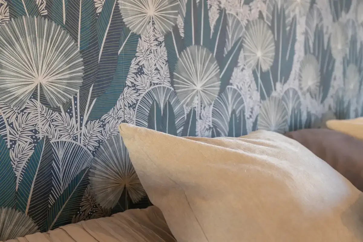 A bedroom wall with patterned wallpaper and a bed pillow.