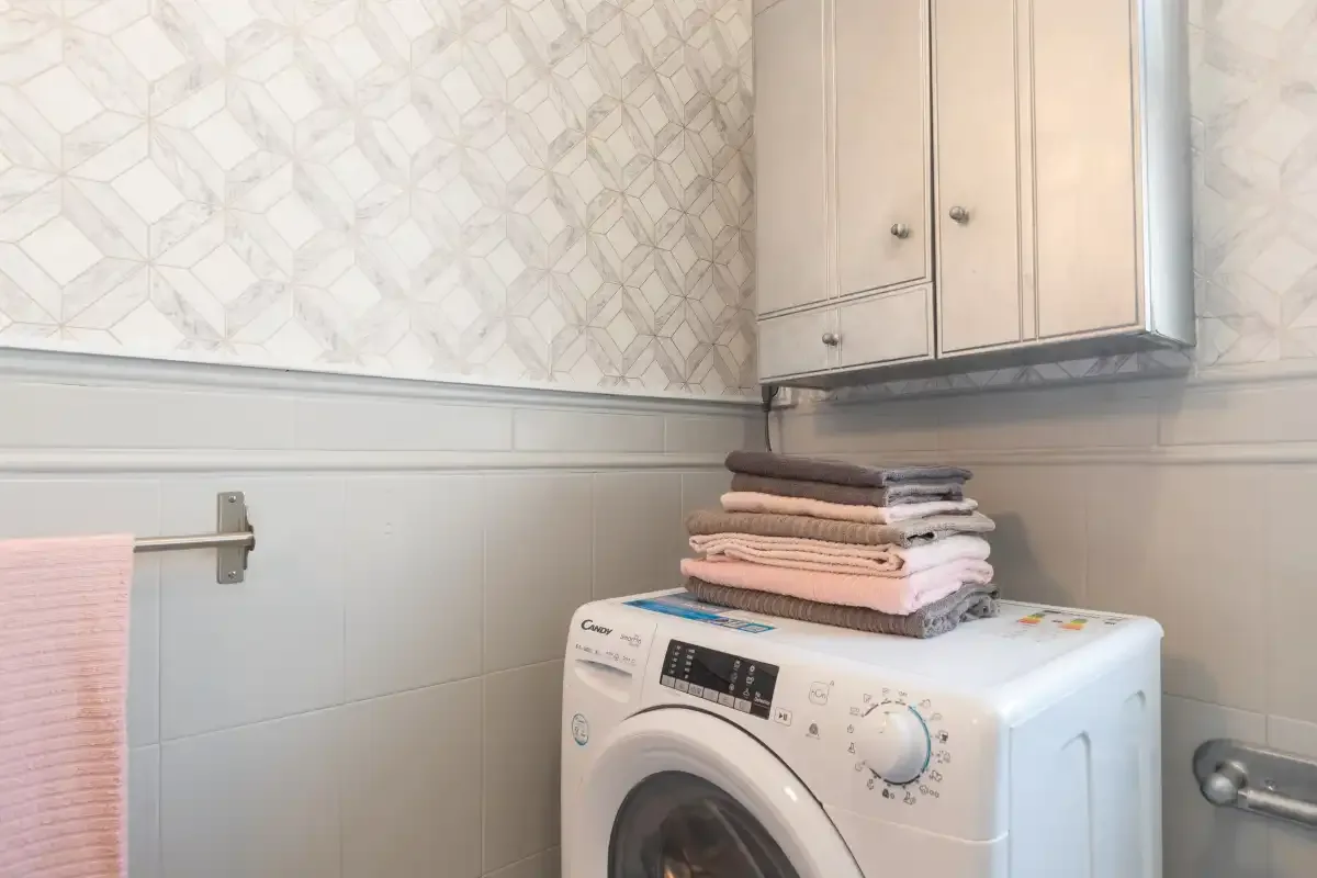 A laundry area with a washing machine and folded towels.