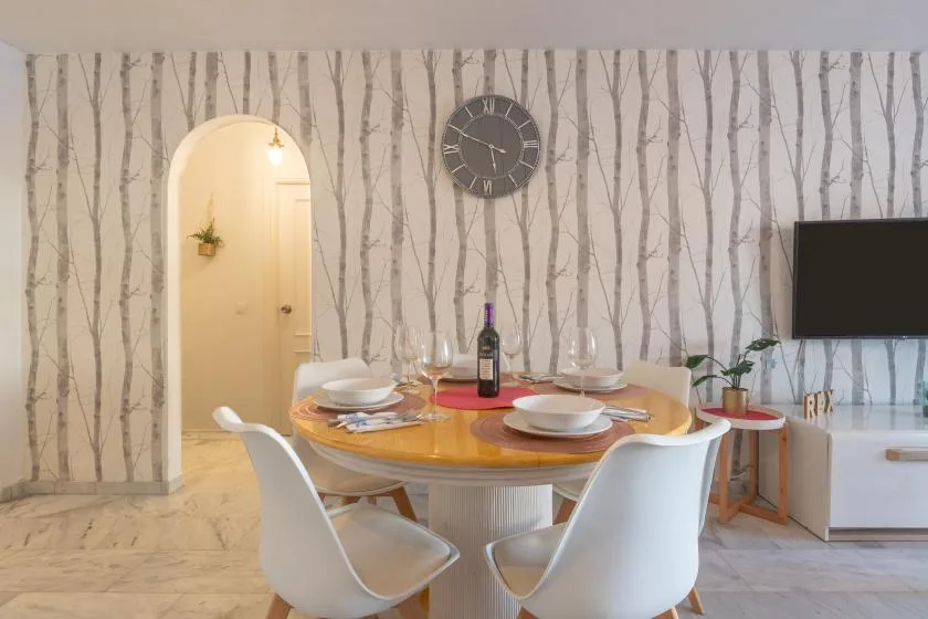 A dining area with a round table set with dishes beside a living room.