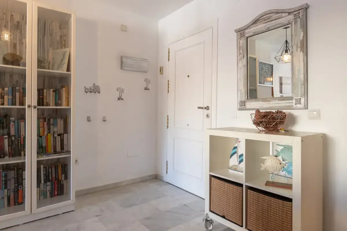 An entryway with a white door, bookcase, and storage cabinet.