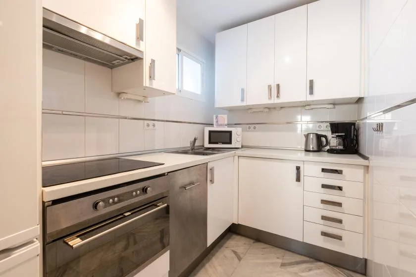 A bright kitchen with white cabinets, a tiled backsplash, and built-in appliances.