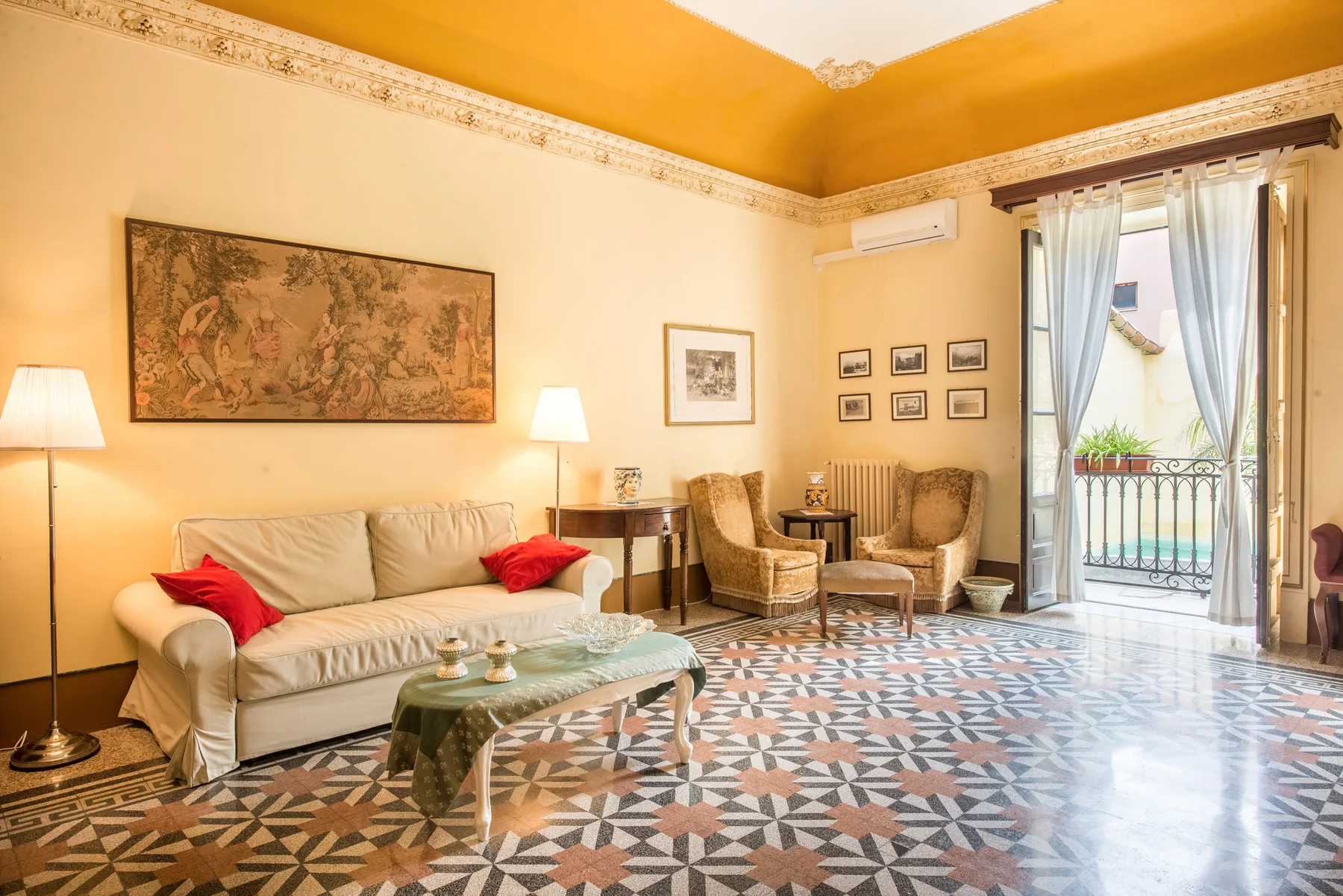 A living room with a sofa, armchairs, and a patterned tile floor.