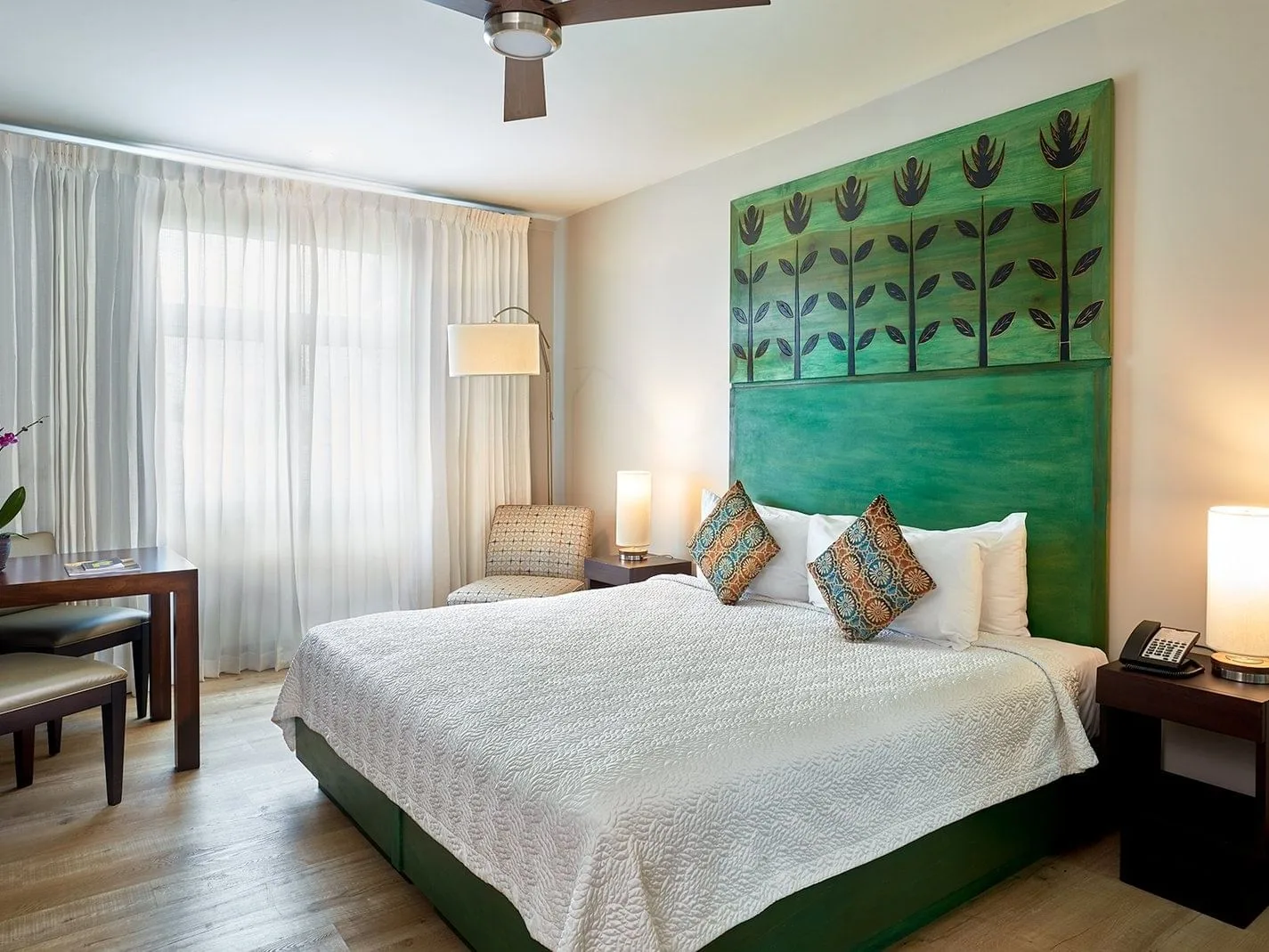 Standard Deluxe with Kitchenette, with a bed featuring a green headboard and modern furnishings.