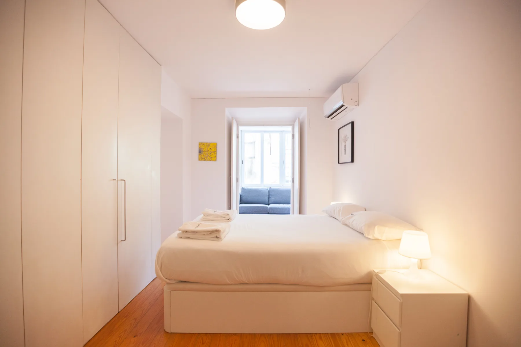 A bright bedroom with a bed, bedside table, and wardrobe.