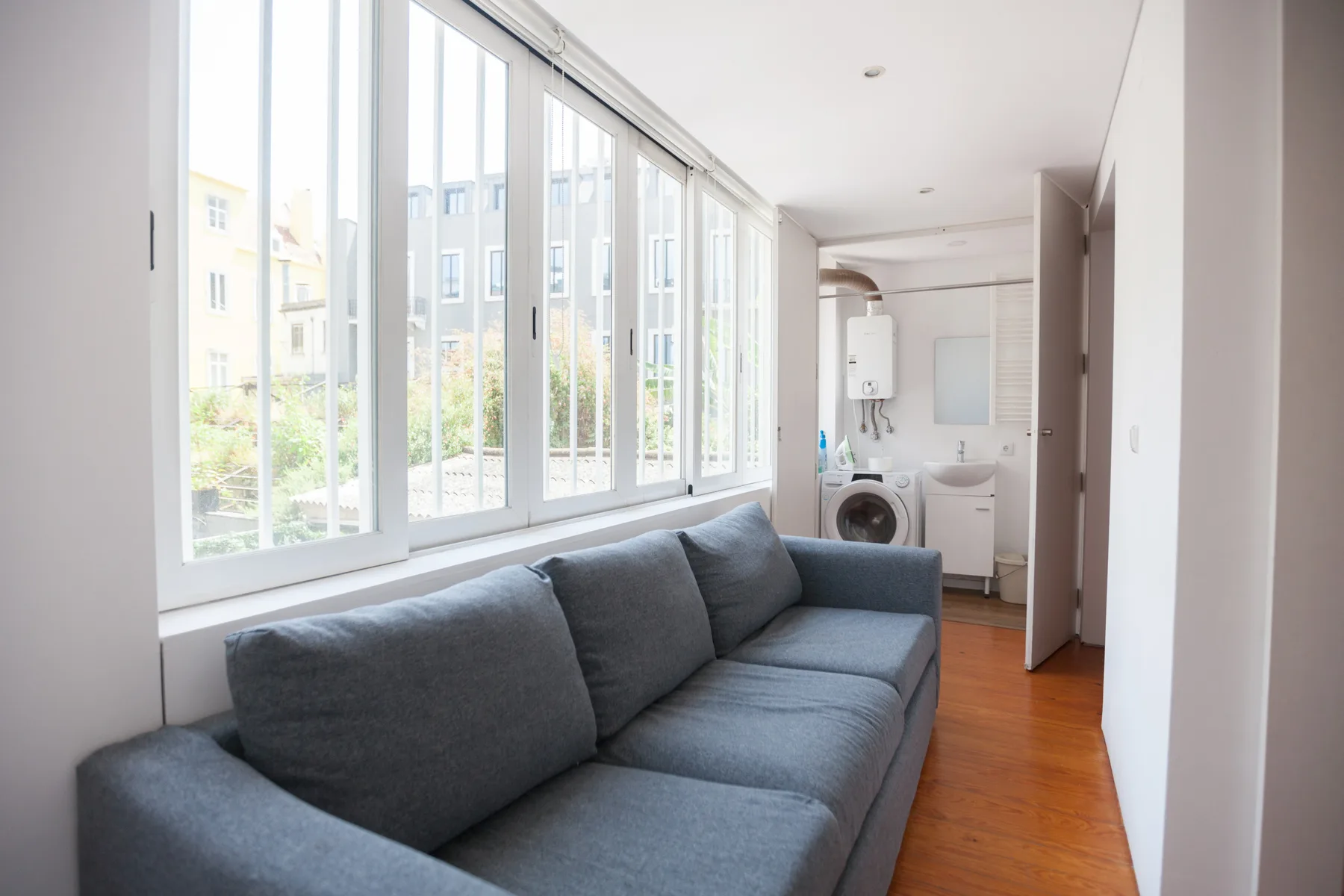 A bright living area with a gray sofa beside a row of large windows.