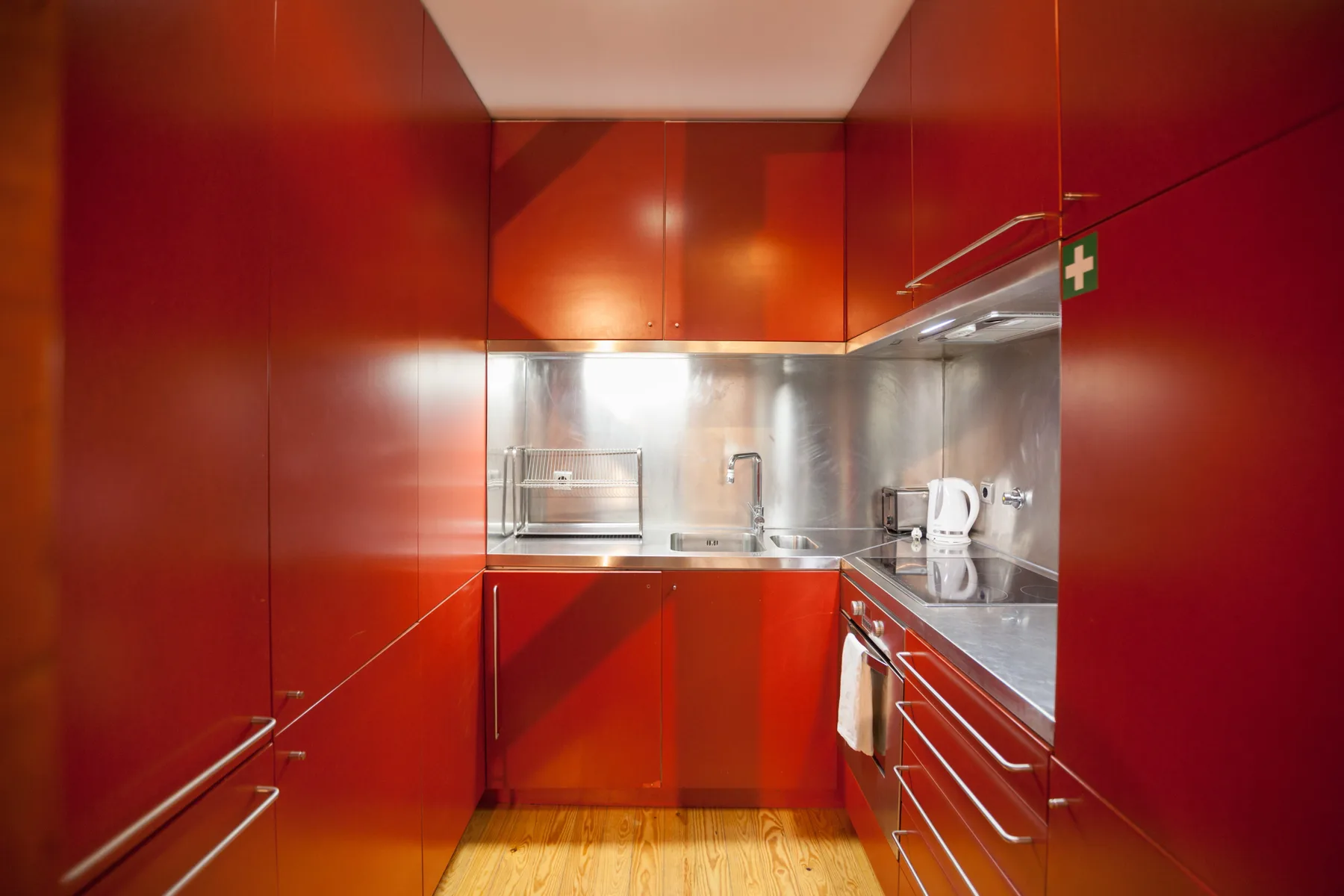 A red kitchen with built-in cabinets and a kettle on the counter.