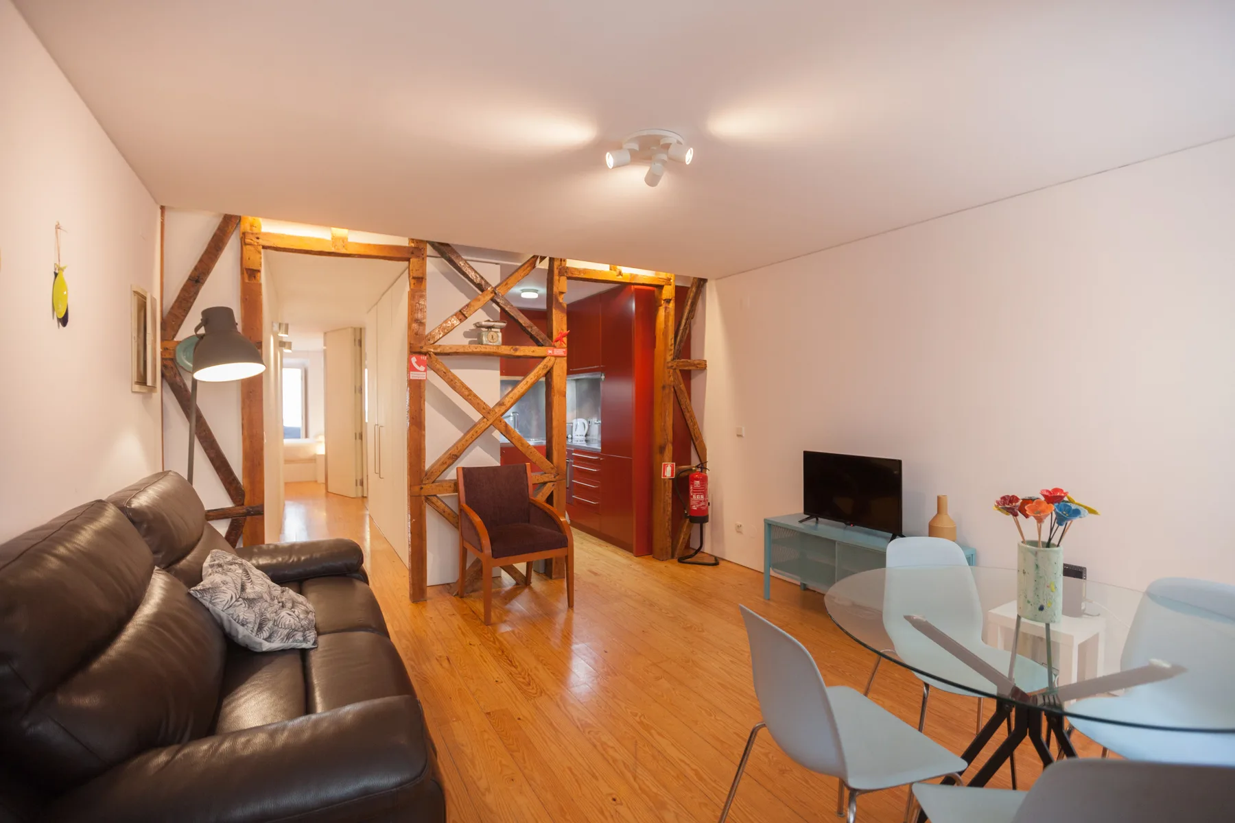 Living and dining area with seating, a glass table, and a television.