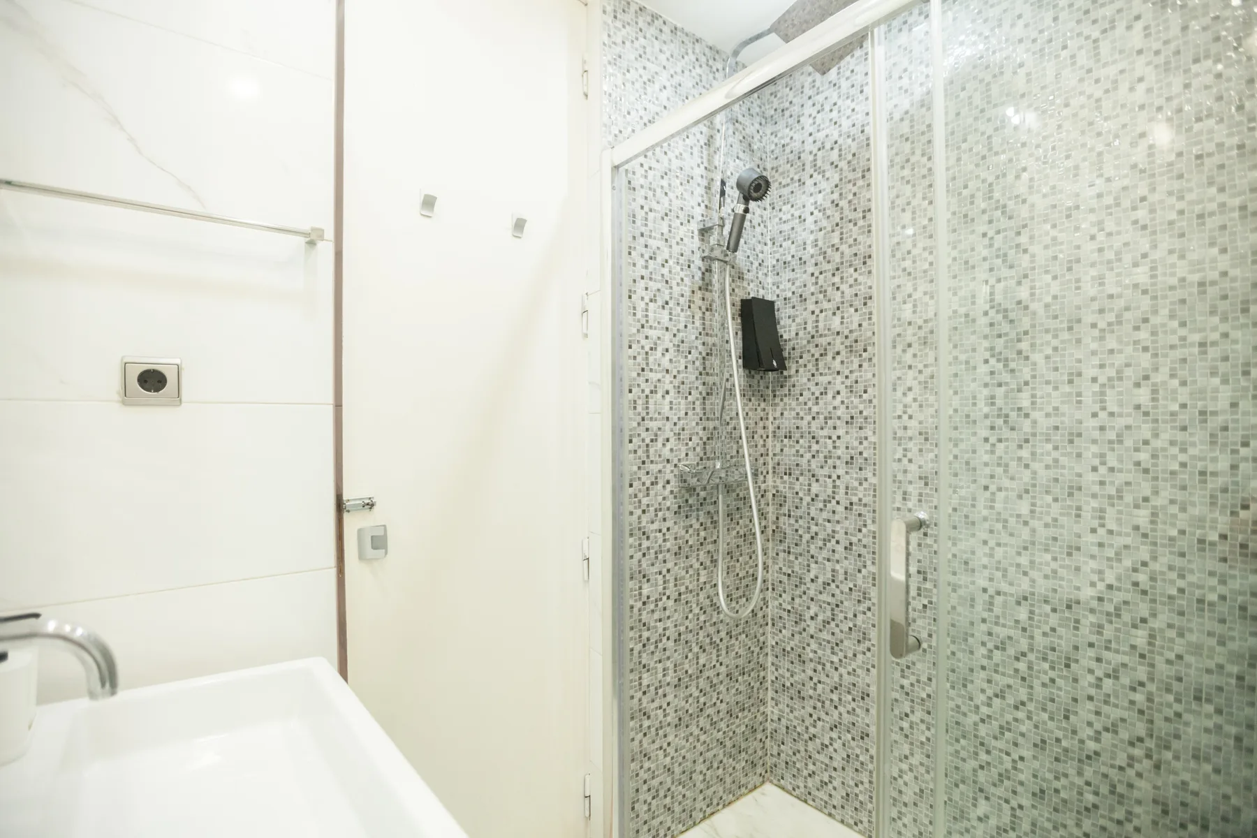 A bathroom with a glass-enclosed shower and a sink.
