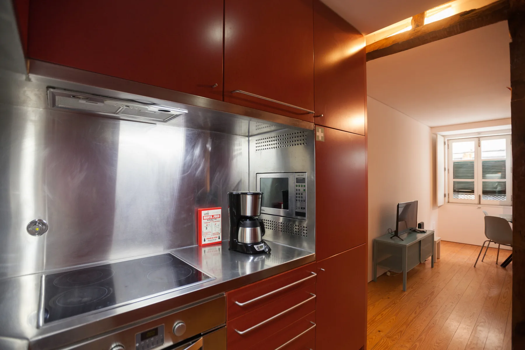A compact kitchen opens into a bright living area with a window.