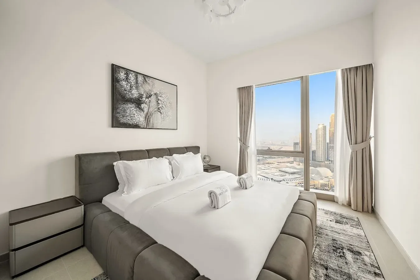 Un dormitorio luminoso con una cama bien tendida y una gran ventana con vistas a la ciudad.