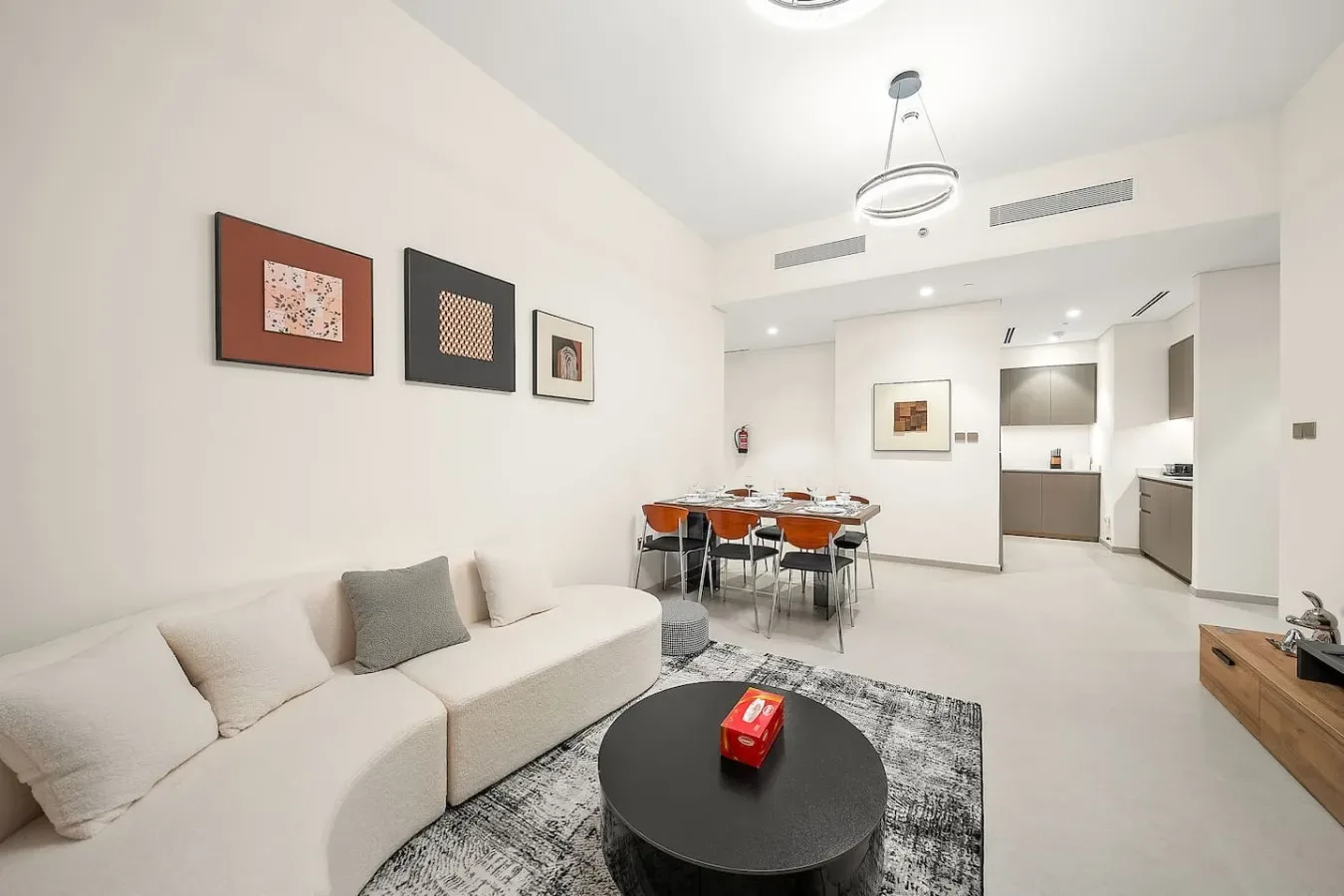 Una sala luminosa con sofá seccional, mesa de centro y comedor.