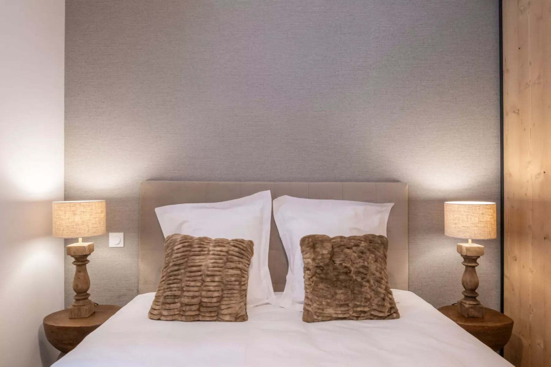 A bedroom with a neatly made bed and matching bedside lamps.