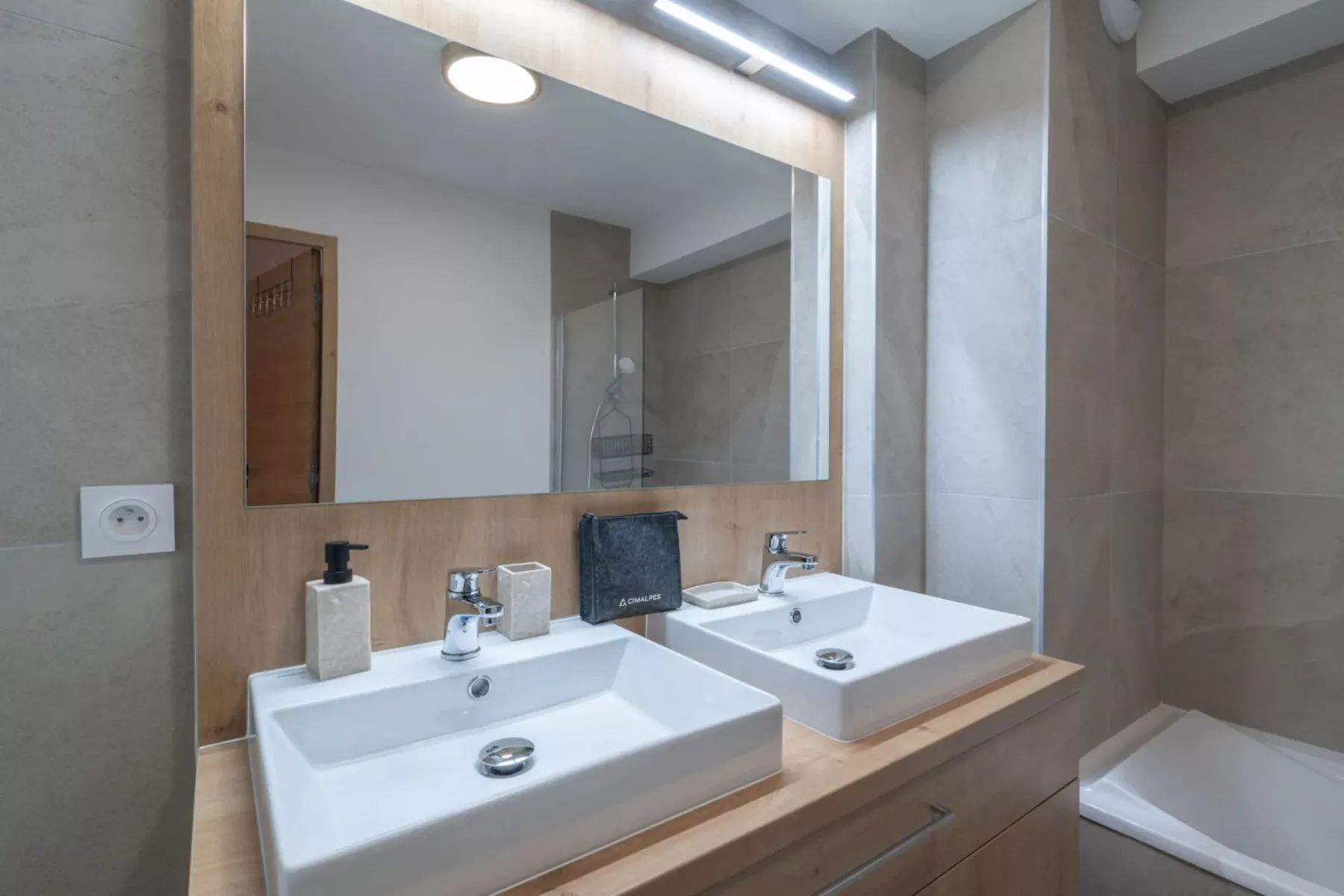 A bathroom vanity with two sinks and a large mirror.