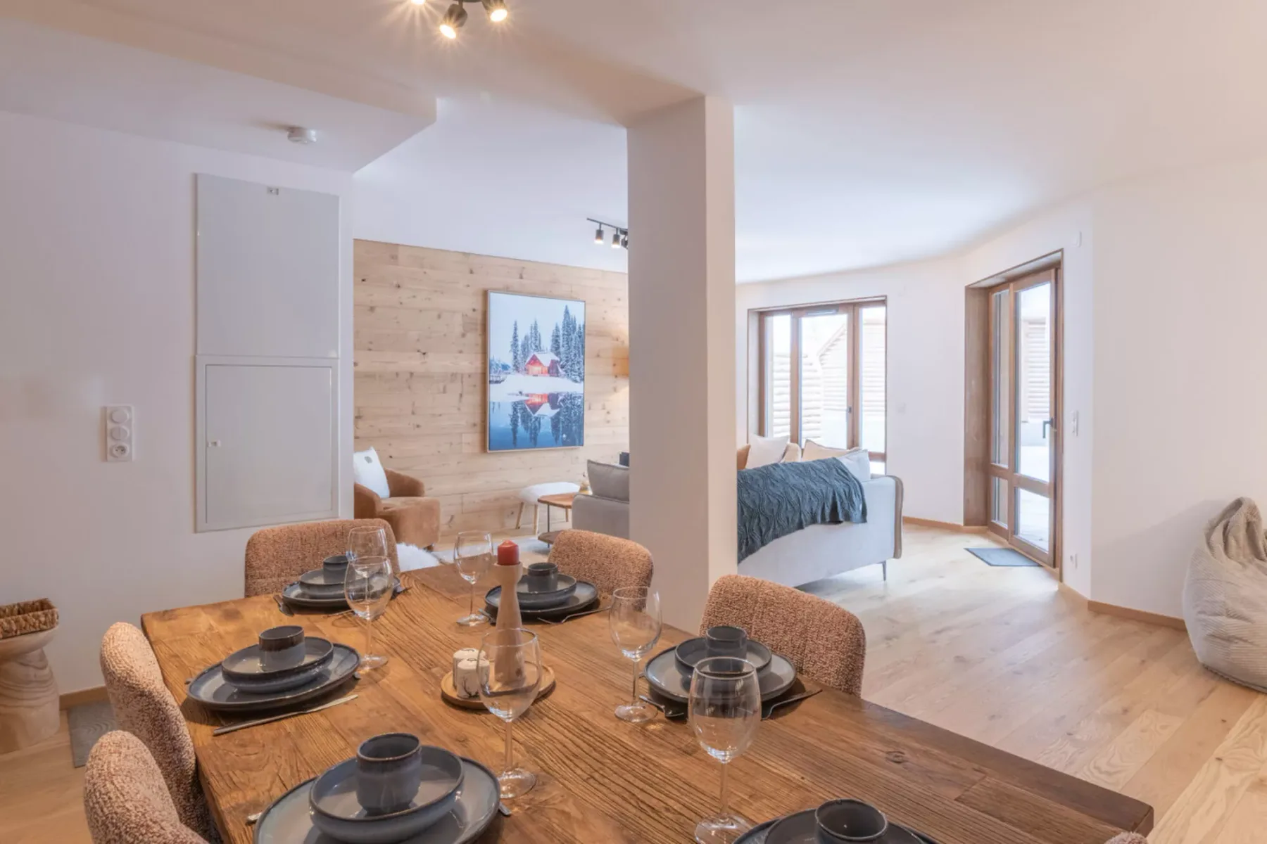 A bright open-plan living and dining area with a wooden dining table.