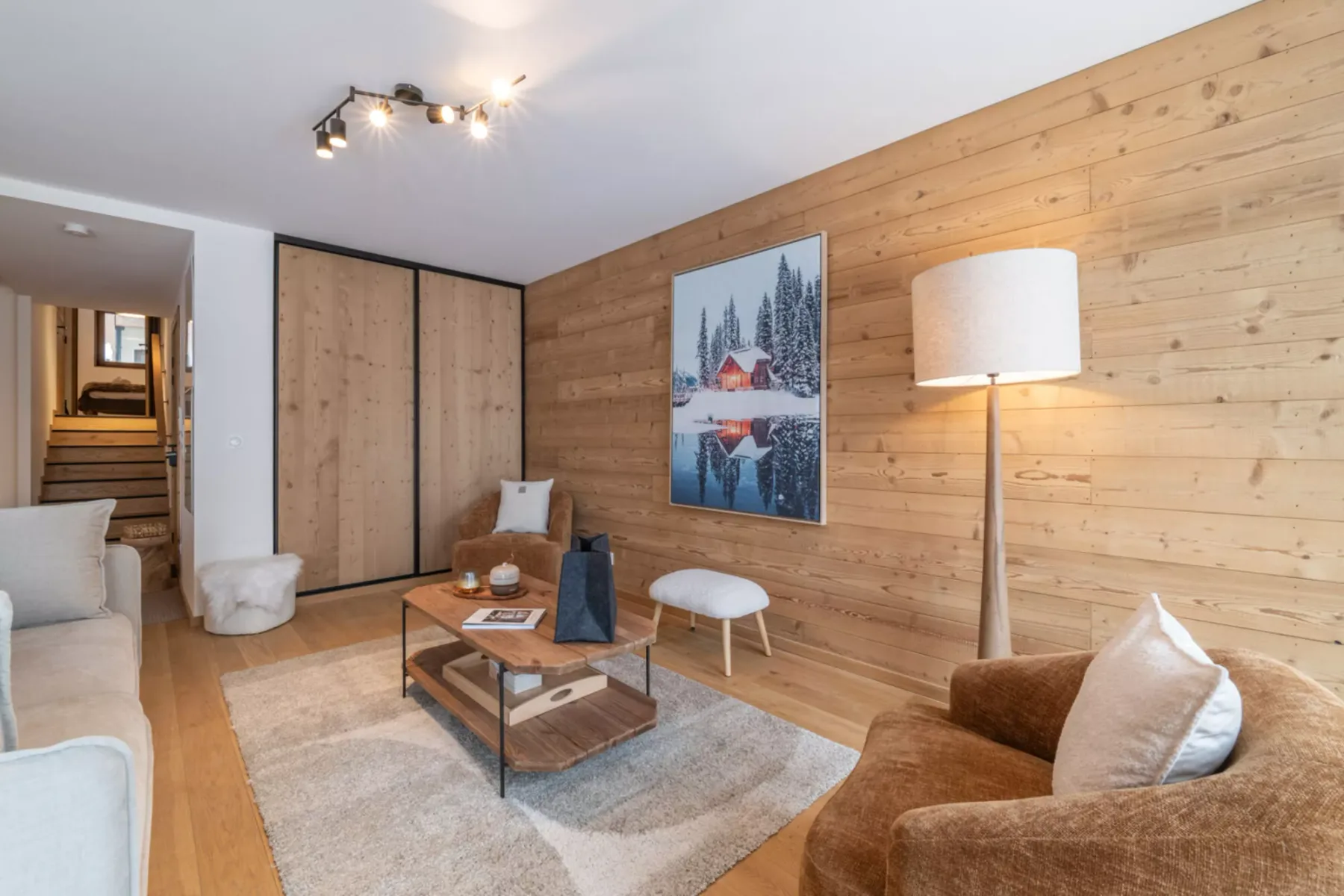 A wood-paneled living room with seating around a coffee table and a framed landscape print.