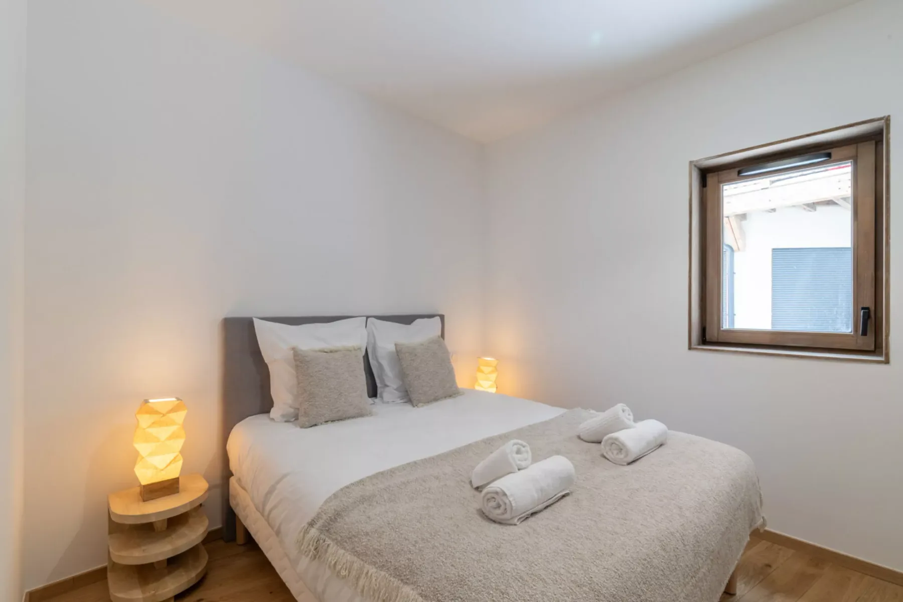 A bedroom with a neatly made bed and a window.