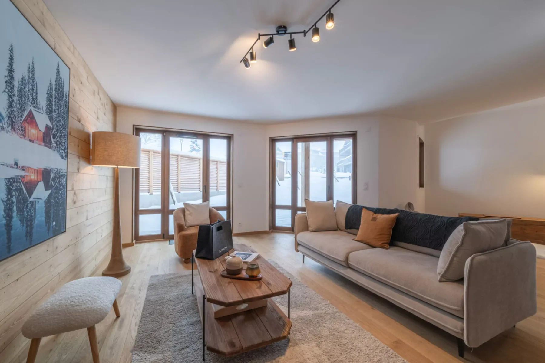 A living room with seating, a coffee table, and large windows.