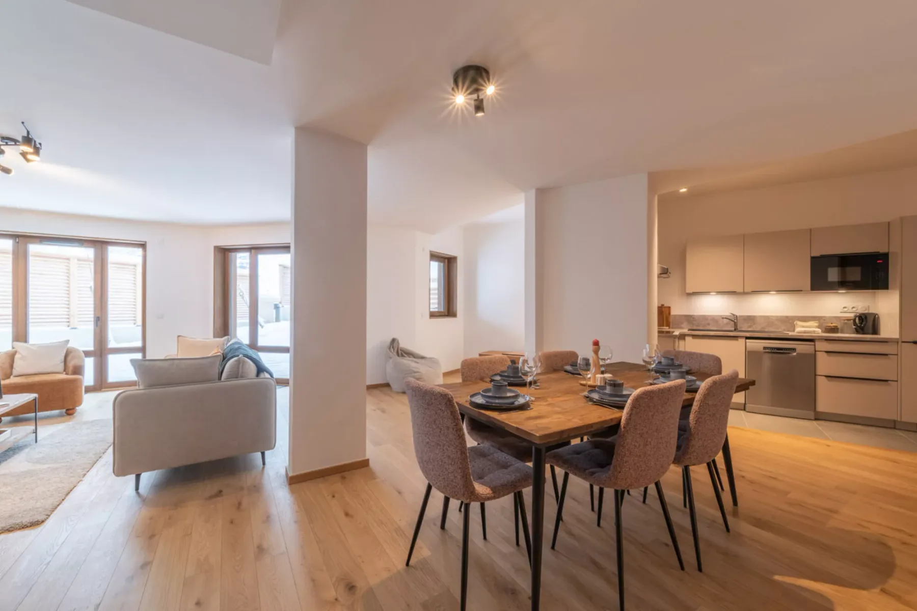 A bright open-plan living and dining area with a kitchen in the background.