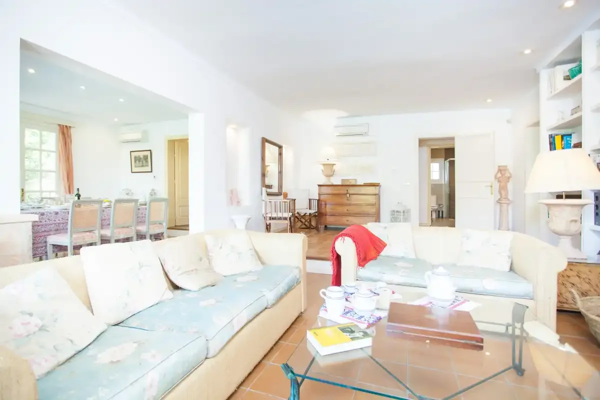A bright living room with pale seating and a glass coffee table.
