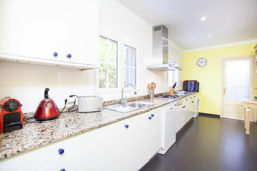 A bright kitchen with a long counter, sink, and cooking area.