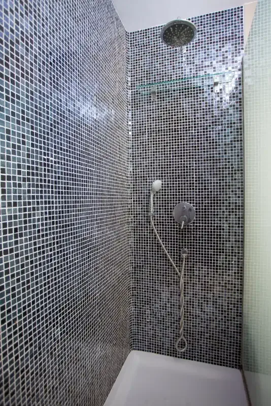 A tiled shower with a handheld showerhead and overhead fixture.