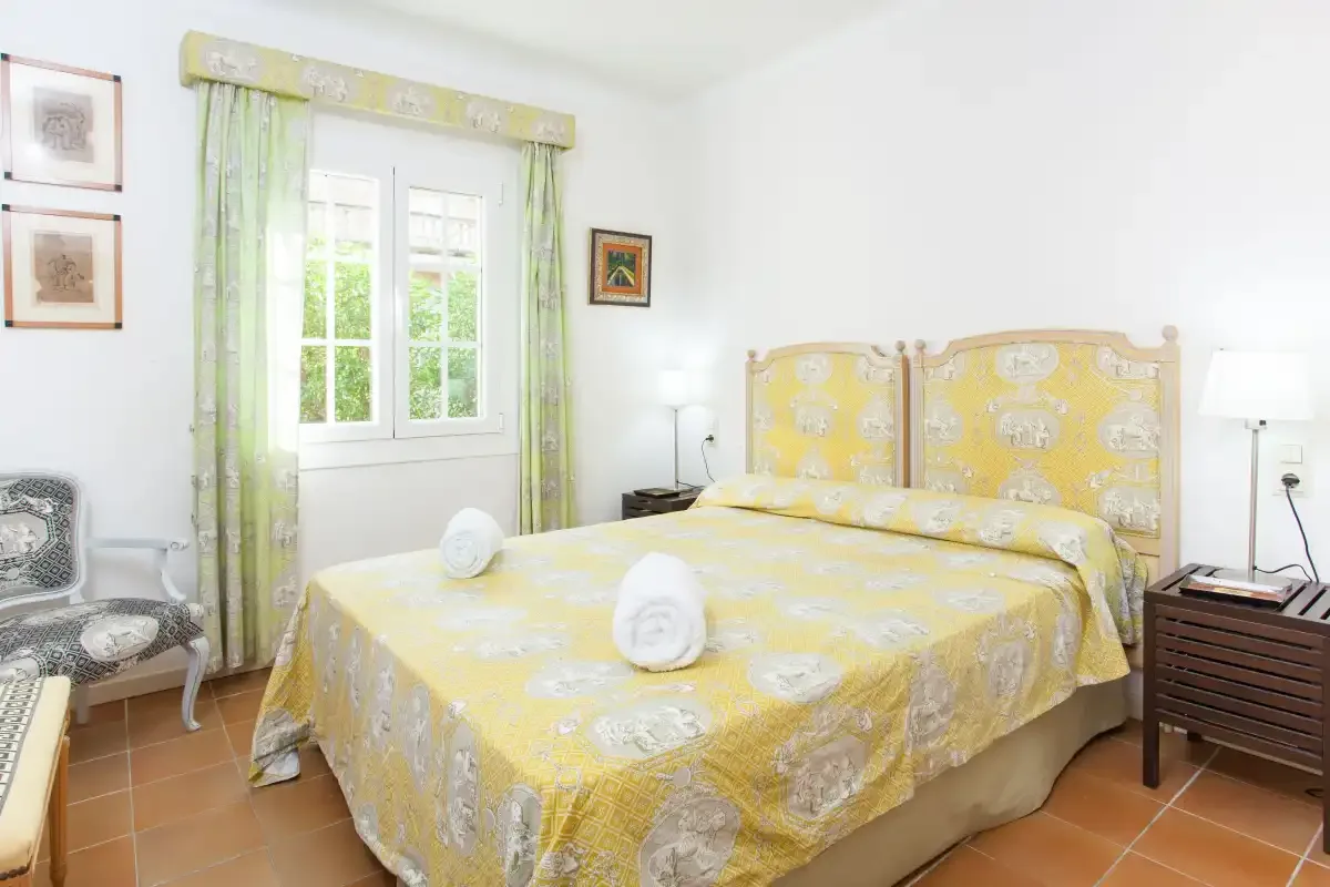 A bedroom with a yellow bedspread, green curtains, and a window.