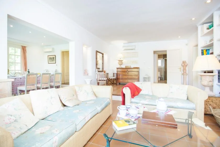 A bright living room with pale seating and a glass coffee table.