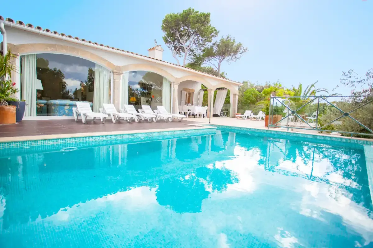 A swimming pool beside a villa patio with outdoor seating.