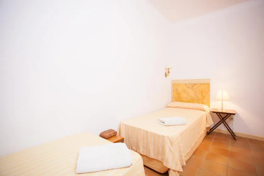 A bedroom with a neatly made bed and a small bedside table.