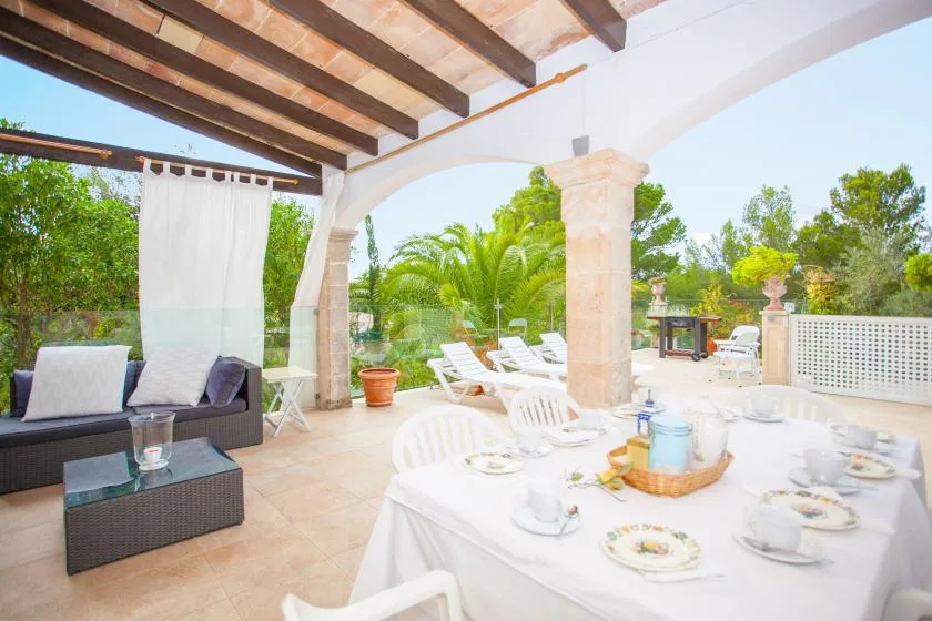 A covered patio dining area with a set table and outdoor seating.