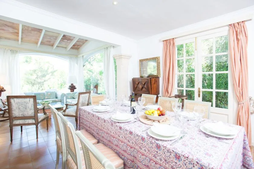 A bright dining room with a set table beside large windows.