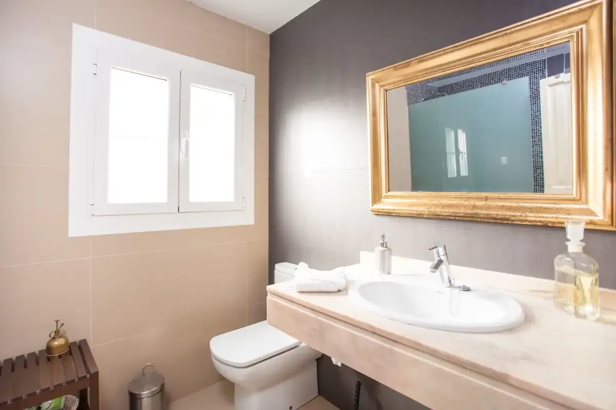 A tiled bathroom with a sink, mirror, and window.