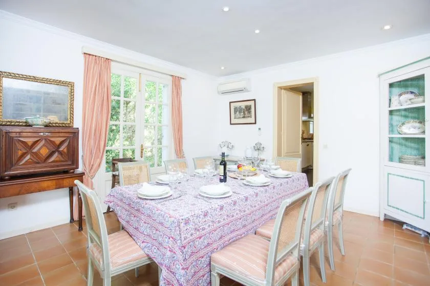 A bright dining room with a set table beside tall windows.