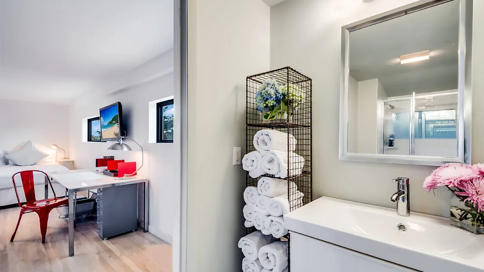 Un tocador de baño luminoso con espejo y toallas ordenadas.