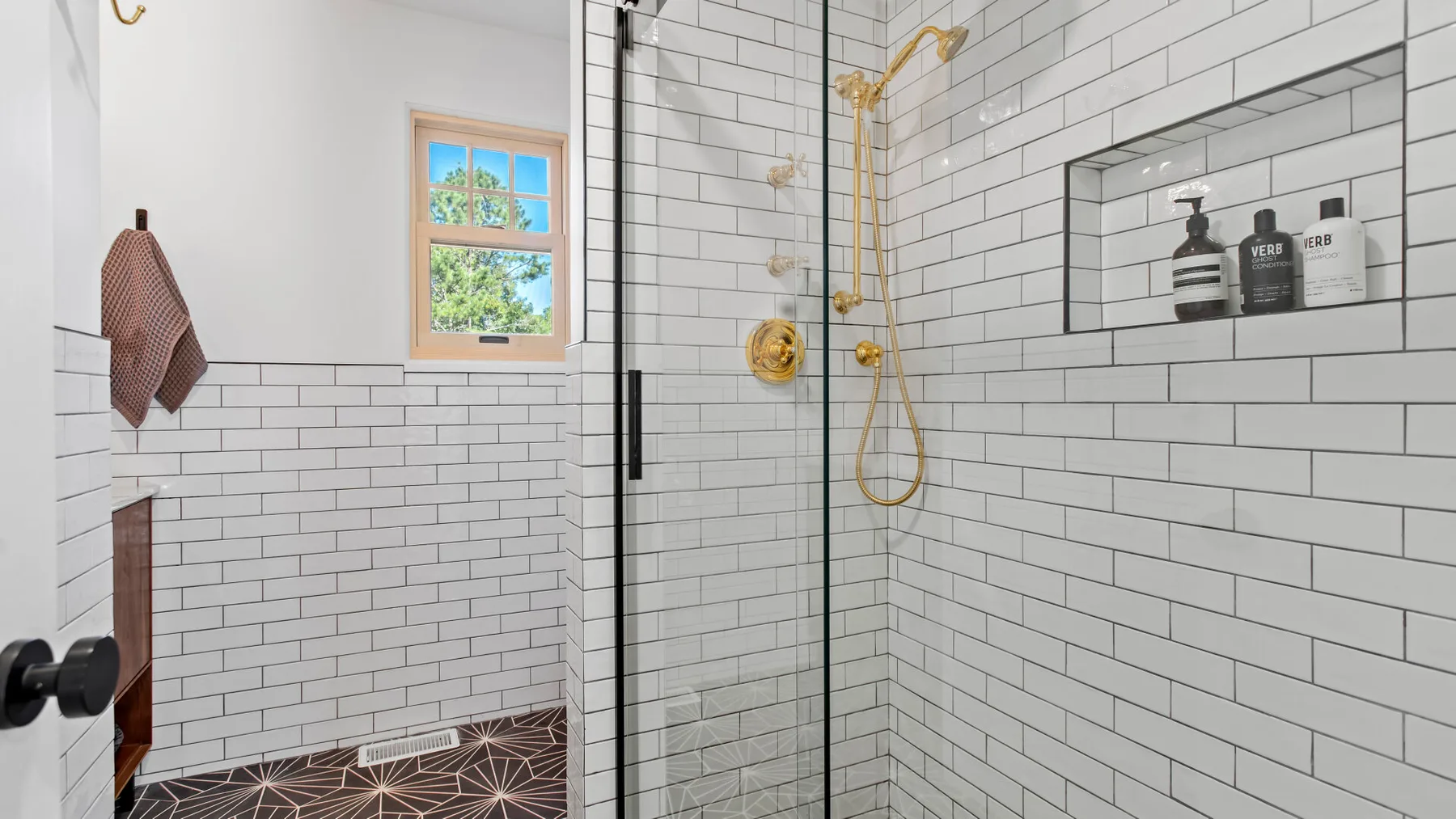 A tiled bathroom with a glass shower and a small window.