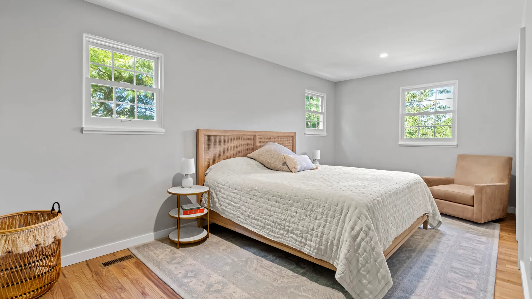 A bright bedroom with a bed, bedside table, and armchair.