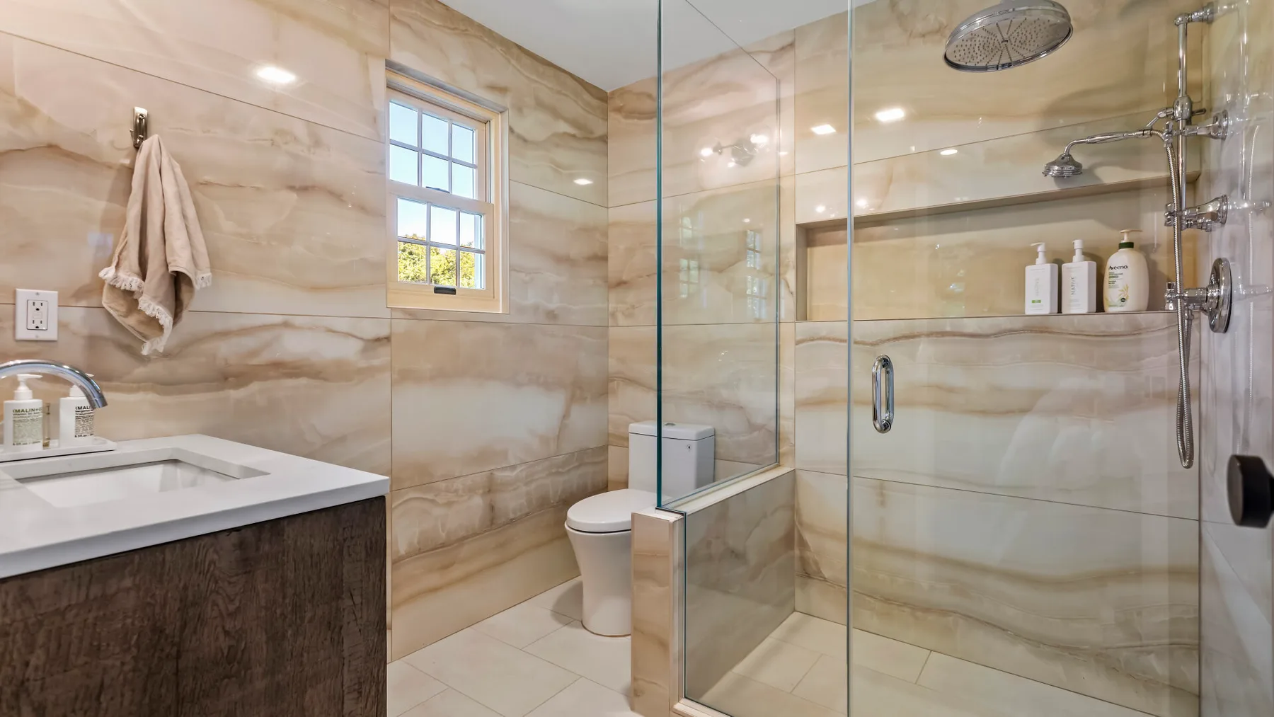 A bathroom with a glass shower, sink, and toilet.