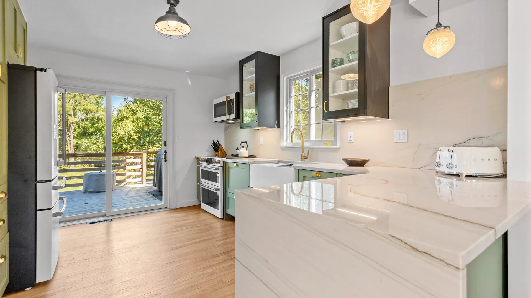 A bright kitchen with pale counters and glass doors opening onto a deck.
