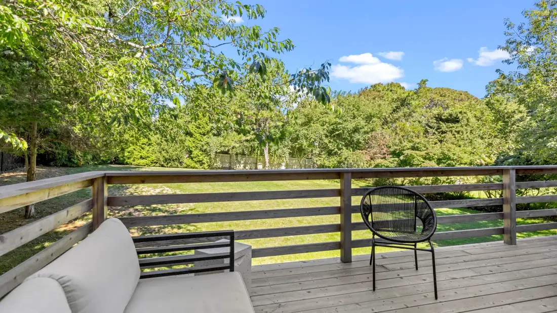 Una terraza de madera con asientos al aire libre da a un paisaje arbolado.