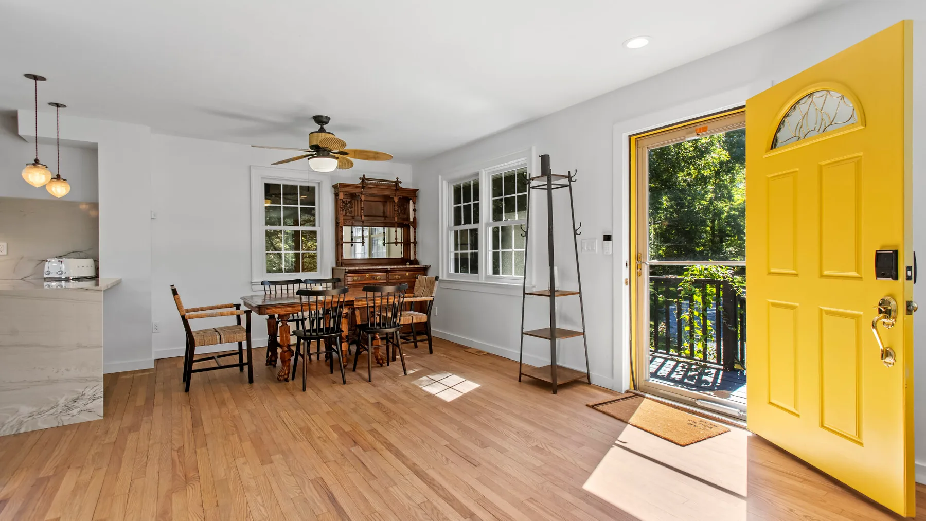 A dining area with a wooden table and chairs beside an open yellow door.