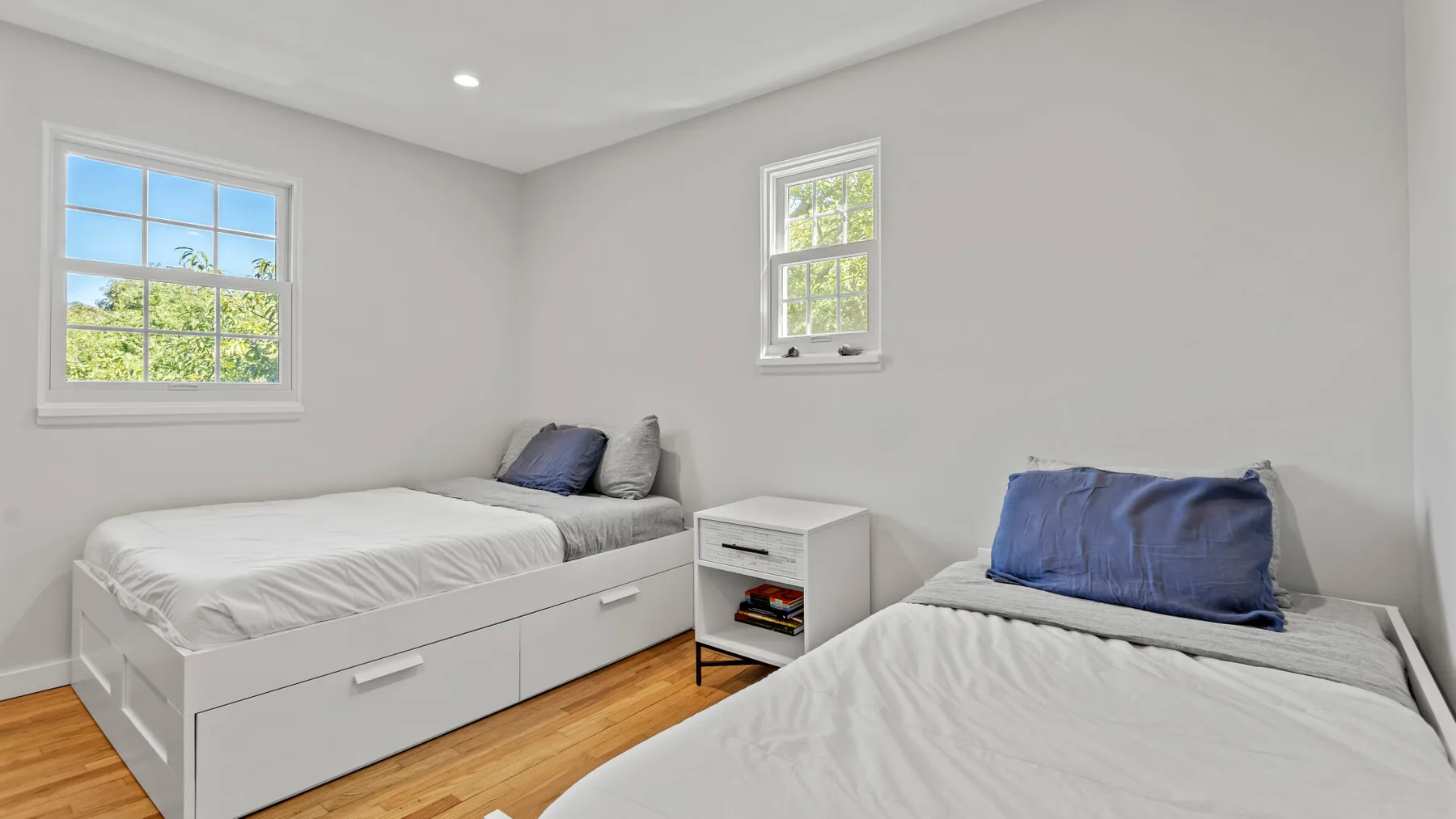 Bedroom with two beds, a small bedside table, and windows.