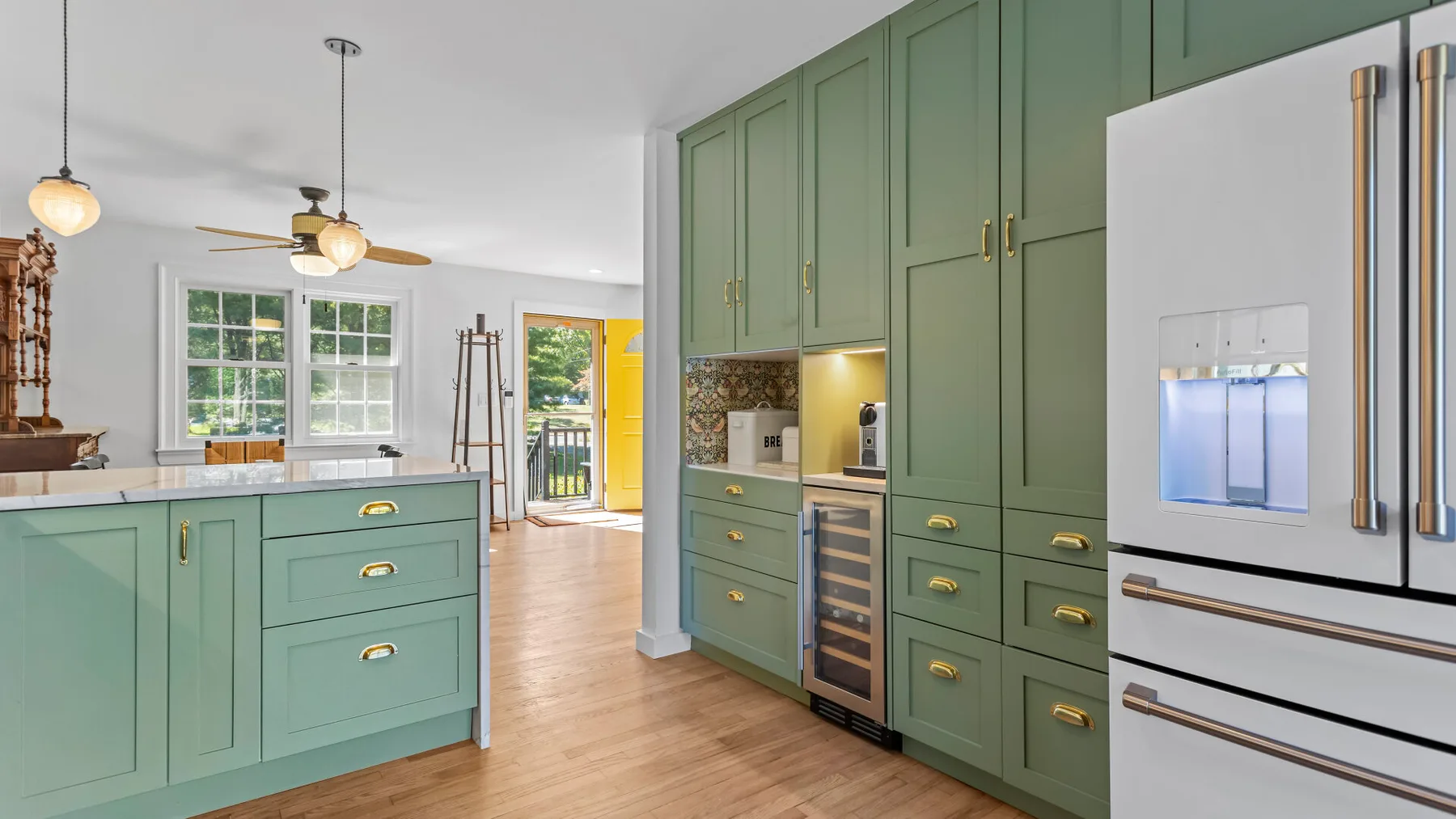 A green-cabinet kitchen with a central island and stainless steel refrigerator.