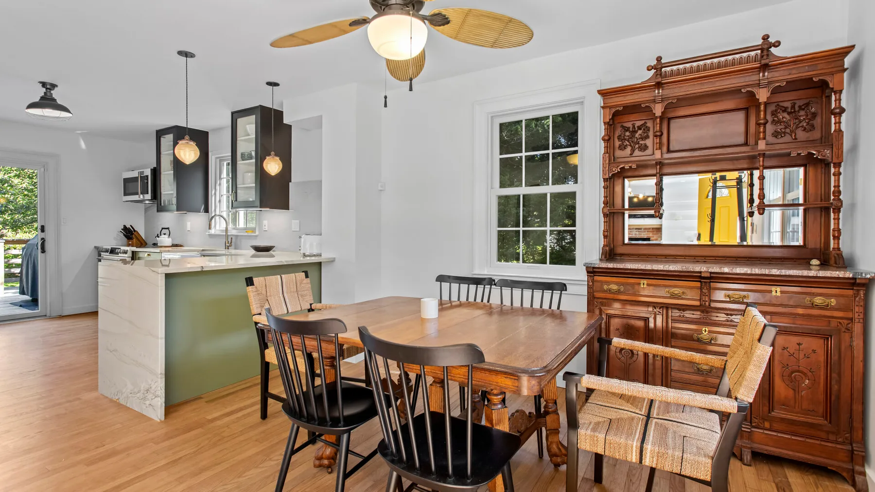 A dining area with a wooden table and chairs beside an open kitchen.