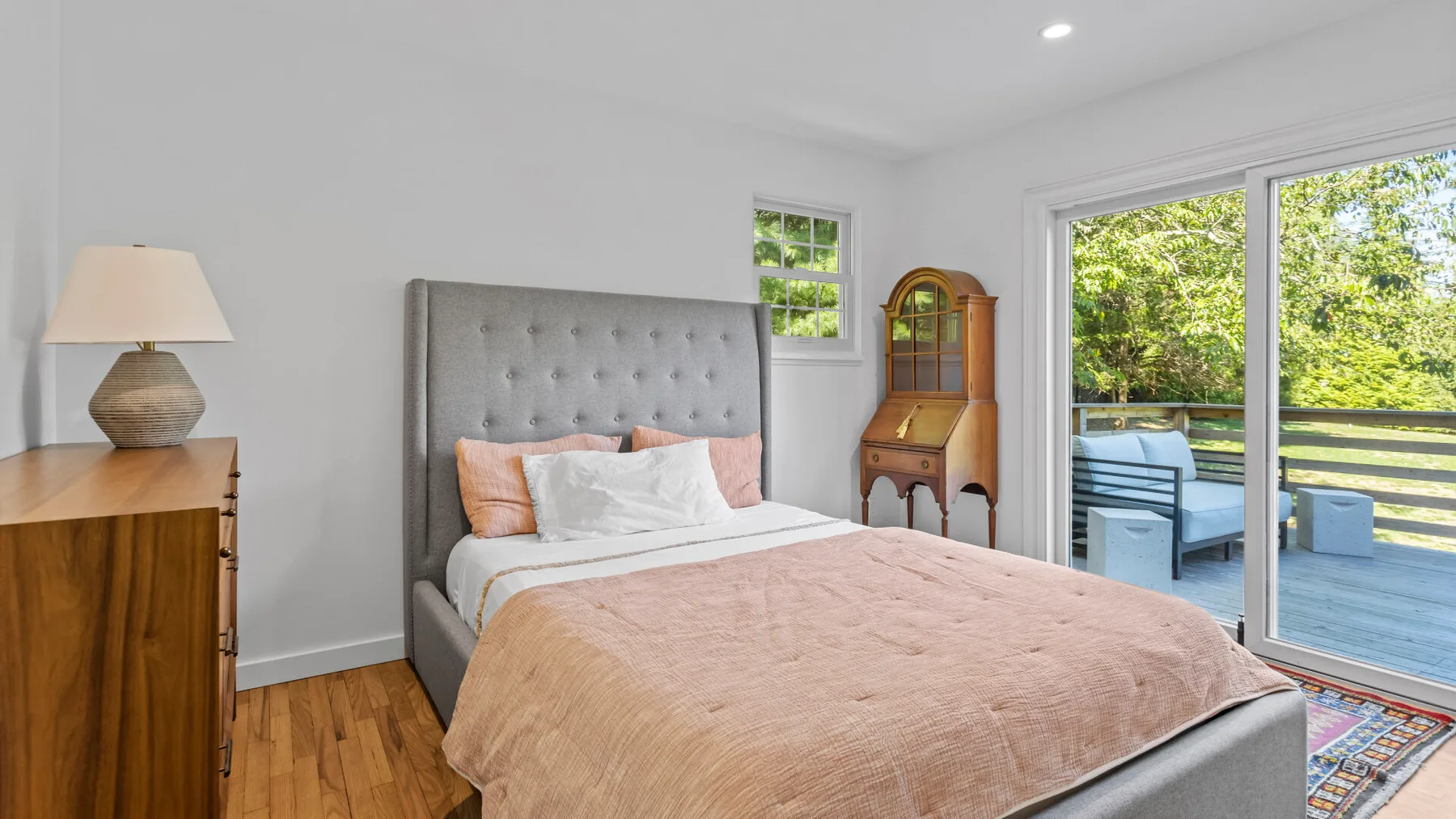 A bedroom with a bed beside large glass doors opening onto a patio.